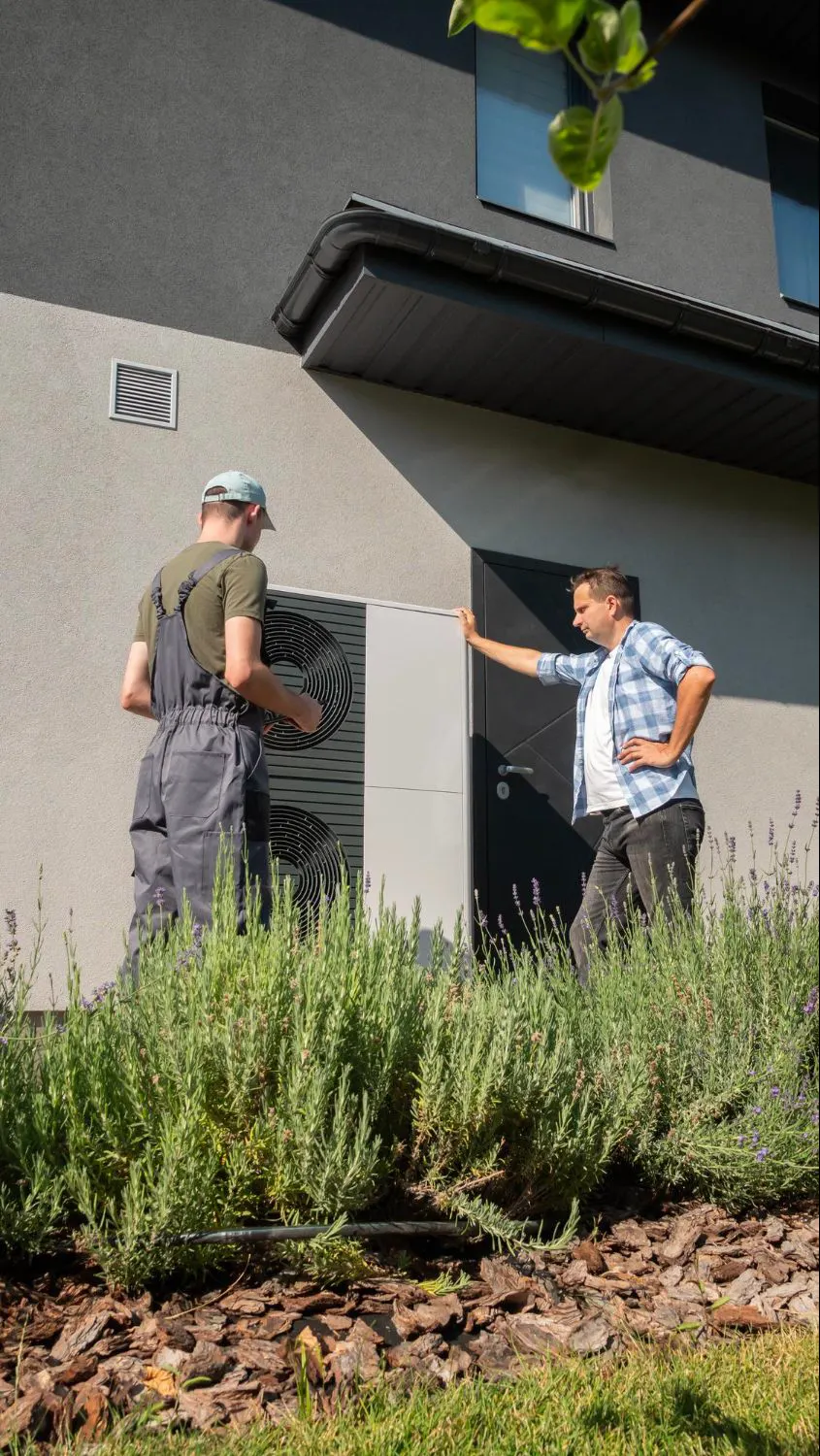 Two technicians reviewing an outdoor AC condenser at a home