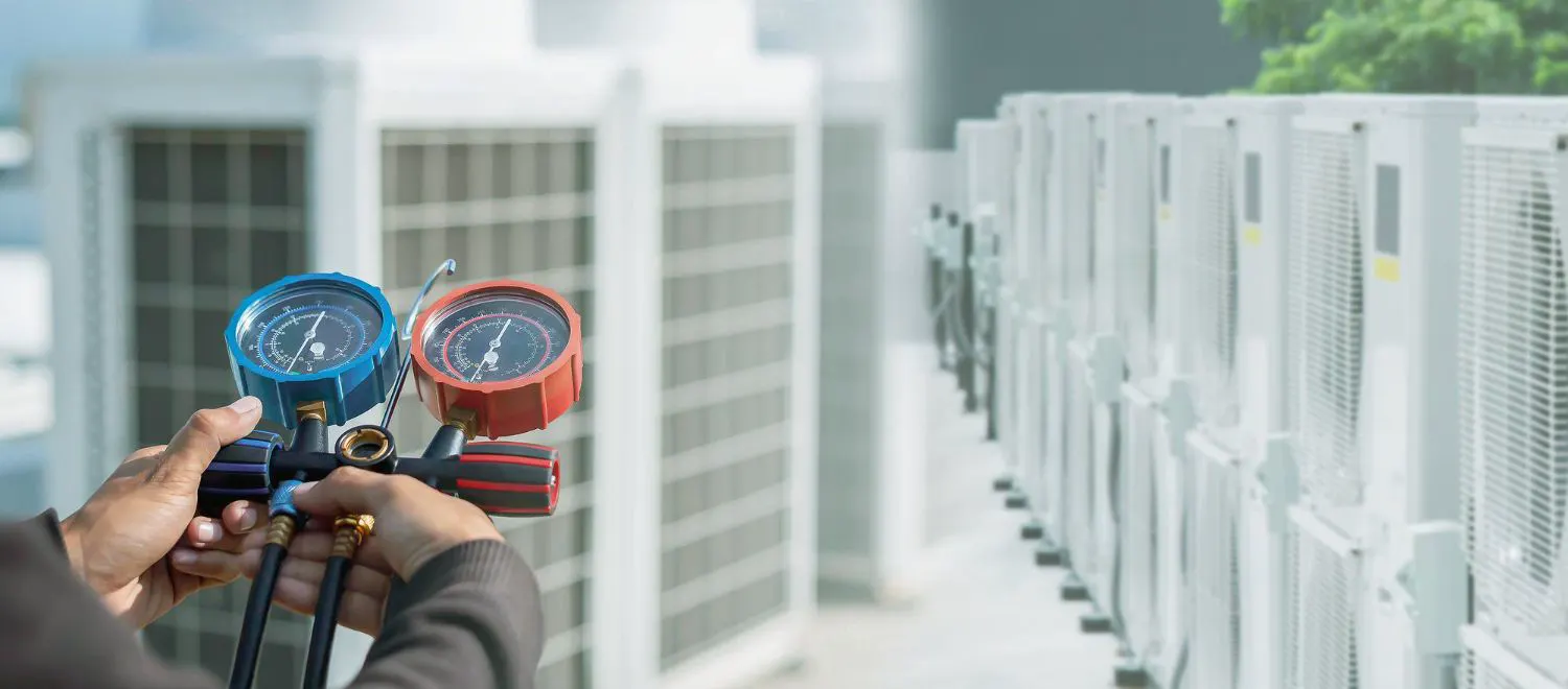 Technician reading refrigerant gauges on an outdoor AC condenser